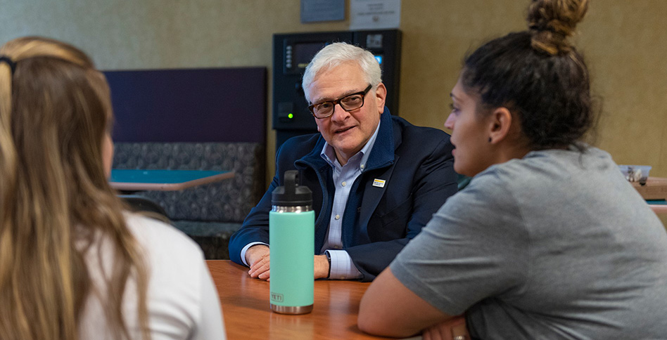 President Foley speaking with students around a table