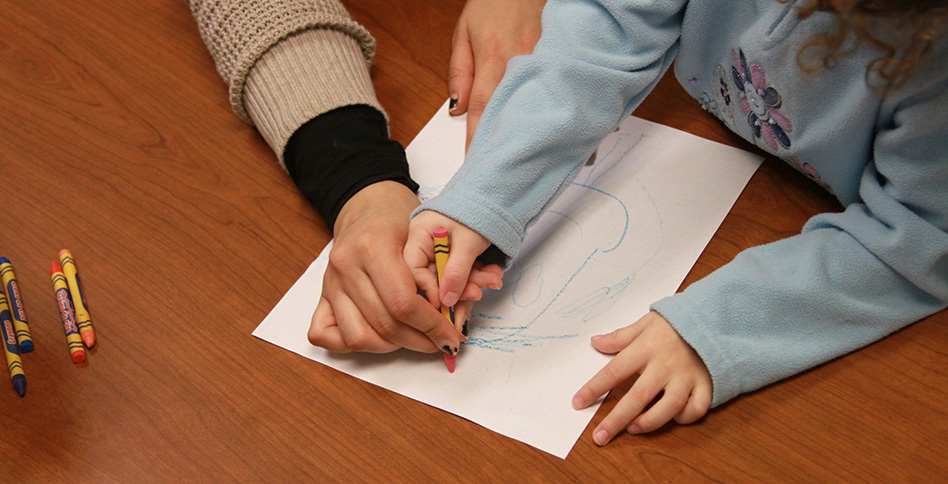 Adult hands helping child hand to write