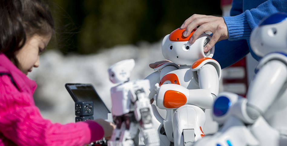 Children touching small robots