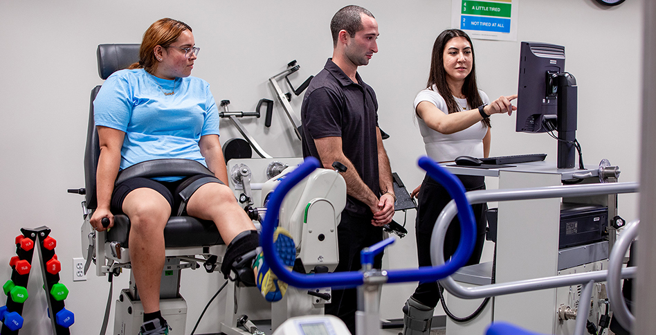 Students working on rehabilitation equipment with trainer