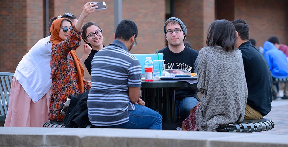 Students take pictures around outside table