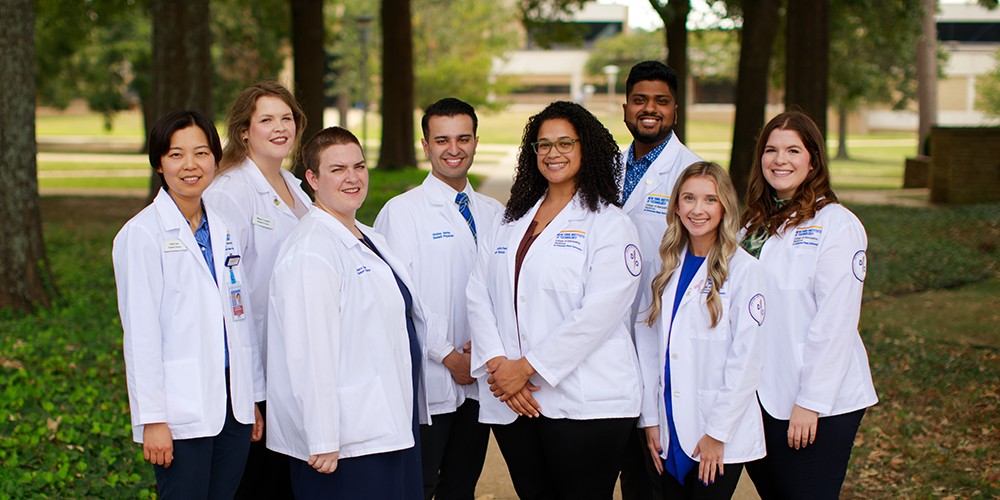 Students at pose in white coats.